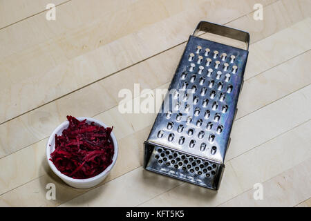 Beetroots grated on shavings. Wooden dining table. Black background. Stock Photo