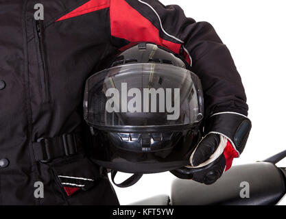 Smiling young man in protective gear holding a helmet under his arm with his red motorbike on a white studio background Stock Photo