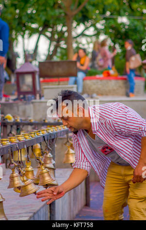 POKHARA, NEPAL OCTOBER 10, 2017: Unidentified businessman touching the bells of different size hanging in Taal Barahi Mandir temple, Pokhara, Nepal Stock Photo