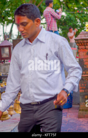 POKHARA, NEPAL OCTOBER 10, 2017: Unidentified businessman touching the bells of different size hanging in Taal Barahi Mandir temple, Pokhara, Nepal Stock Photo