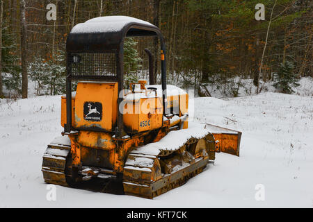 Rusty old John Deere 450C dozer parked in a field in the snow in the Adirondack Mountains, NY, USA. Stock Photo