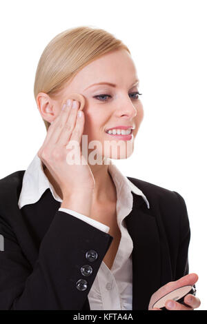 Attractive businesswoman applying foundation. Isolated on white Stock Photo