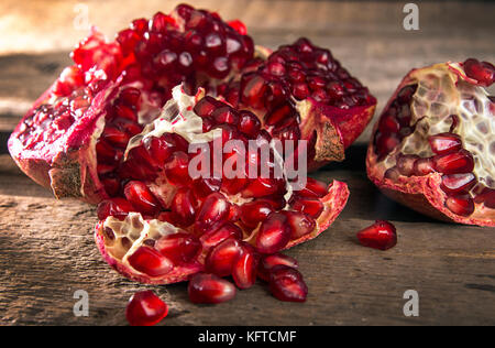 Broken pomegranate. Pomegranate grains. Pomegranate close up on wooden table Stock Photo