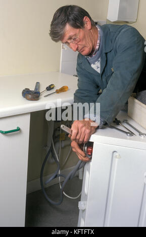 mature plumber fixing washing machine Stock Photo