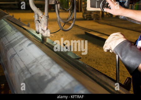 Male worker operating automated steel welding machine Stock Photo