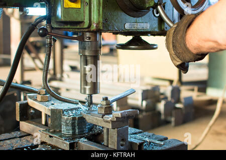 Worker operating stainless steel drilling machine cooled by water Stock Photo