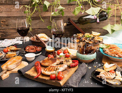 Overhead of dinner table. Assorted delicious grilled barbecue meat and seafood with vegetable.Pork grilled steaks, grilled salmon trout, mussels, shri Stock Photo