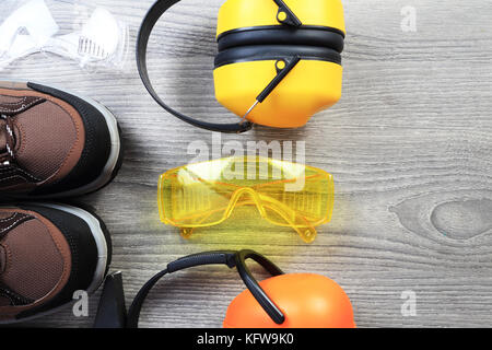 Protective working wear close-up. Safety glasses and headphones from above. Safety working background with copy space on wooden background. Stock Photo