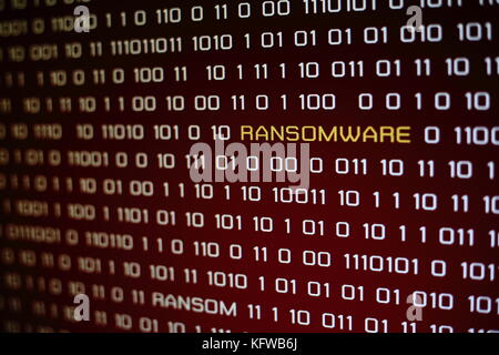 Hacked monitor.  Ransomware. Binary digital numbers on red screen with ransom word on screen. Stock Photo