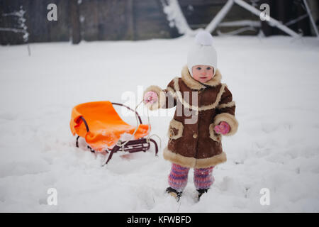 cute girl with sled in snow Stock Photo