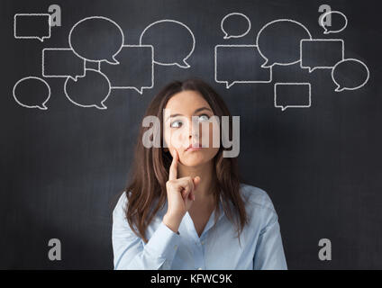 Thinking business woman with speech bubbles on a blackboard. Stock Photo