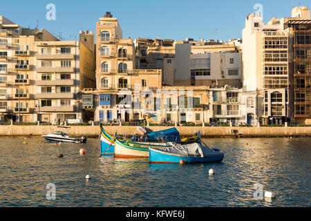 A traditional, brightly painted, Maltese fishing boat or luzzu moored in St Julians Bay Malta Stock Photo