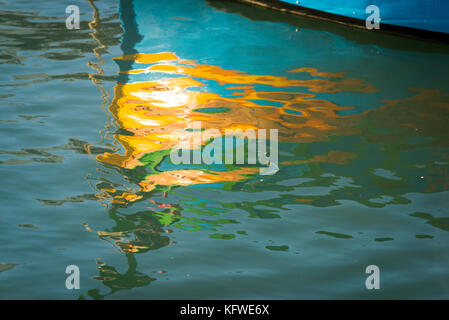 An abstract reflection in the harbour water of a traditional painted Maltese fishing boat or Luzzu Stock Photo