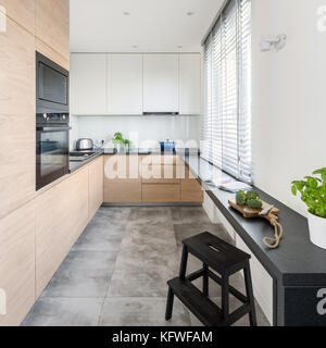Modern kitchen with wooden furniture, granite countertop and big window Stock Photo