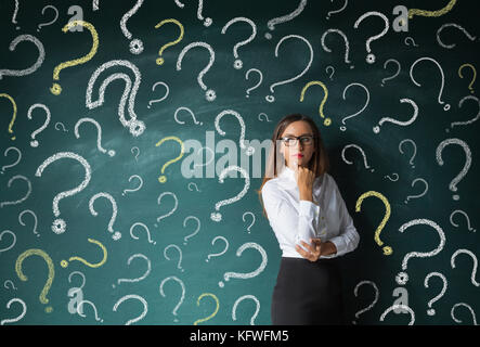 Businesswoman and question mark drawn in chalk on blackboard Stock Photo