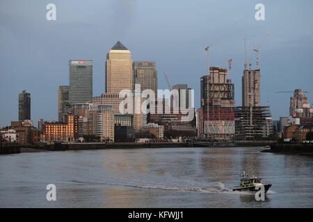 Met Police River boat on The Thames at Limehouse with Canary Wharf in the bacground as the sun goes down over the capital. Stock Photo