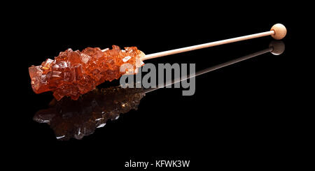 One lying stick of brown sugar with a real reflection on a black glossy background Stock Photo