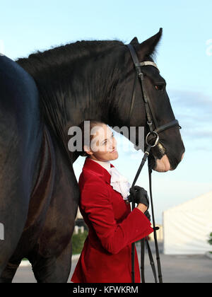 Young woman in dress uniform and her Friesian horse Stock Photo