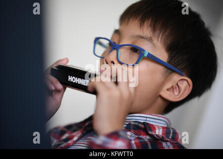 Trossingen, Germany. 1st Nov, 2017. The seven year old music student Yeung Ryan of the Kings College Old Boys Association from Hong Kong warms up with his harmonica in Trossingen, Germany, 1 November 2017. It is the first day of the World Harmonica Festival 2017. Credit: Felix Kästle/dpa/Alamy Live News Stock Photo