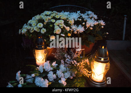 Flowers and candles on grave at night. All Saint's day in Poland Stock Photo