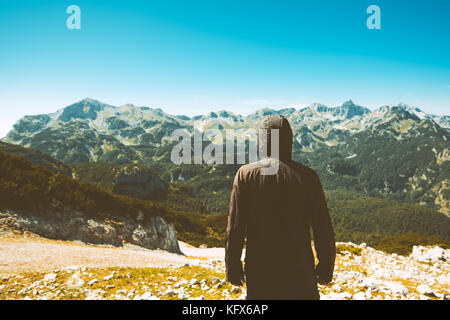 Mountain hiker looking into beautiful landscape. Rear view of the man on the top of the mountain. Stock Photo