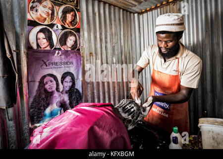 African man washing a clients hair of shampoo Stock Photo