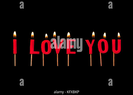 Text inscription, I love You, written with burning candles, isolated on black background. Stock Photo