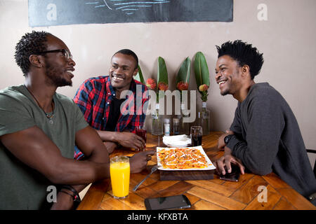 Three men eating nachos at a restaurant Stock Photo