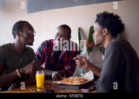 Three men eating nachos at a restaurant Stock Photo