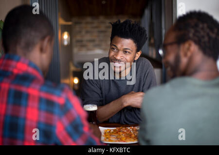 Three men eating nachos at a restaurant Stock Photo