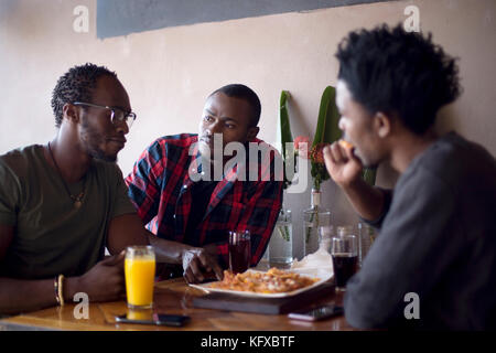 Three men eating nachos at a restaurant Stock Photo