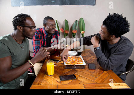 Three men eating nachos at a restaurant Stock Photo