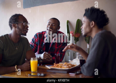 Three men eating nachos at a restaurant Stock Photo