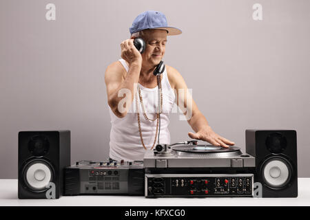 Mature man playing music on a turntable against a gray wall Stock Photo