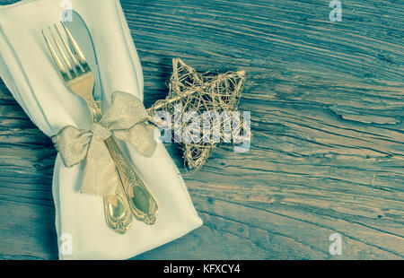Gold tableware and star on rustic wooden background. Vintage tone. Christmas, holiday and celebration setting. Stock Photo