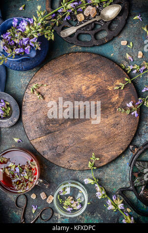 board with fresh herbs and flowers, cup of tea and kitchen tools, top view, copy space Stock Photo