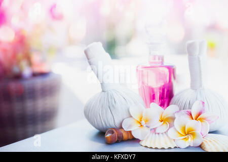 Beautiful spa or wellness  treatment and product with compress balls, lotion, frangipani flower at spring or summer nature background, front view Stock Photo