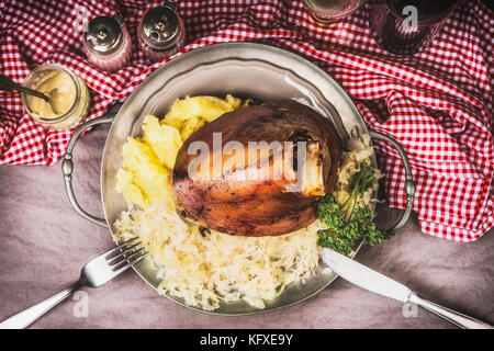 Roasted eisbein with Mashed Potatoes and pickled cabbage served on plate with cutlery , top view Stock Photo