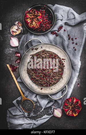 Top view of Healthy vegetarian black lentil salad with pomegranate and cooking ingredients on dark rustic background with napkin. Country dark style Stock Photo