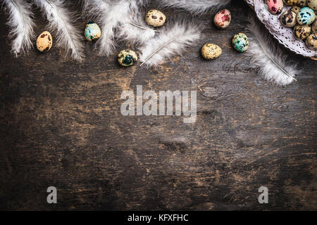Easter background with colored eggs, feathers and basket, top view, border Stock Photo