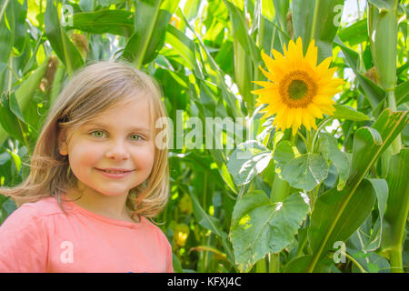 young girl standing in sunflower field Stock Photo