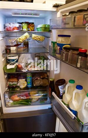 Packed fridge containing food items and drinks including milk, typical UK fridge Stock Photo