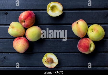 Peaches, whole and sliced, on top of a yellow wooden background surface Stock Photo