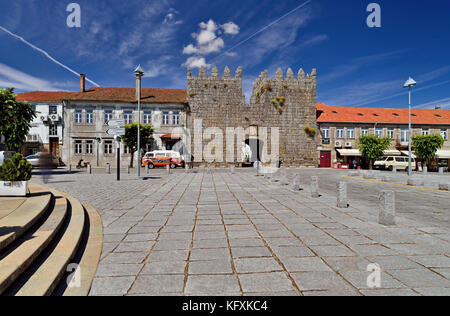 Wide stone paved square with medieval entrance gate leading to historic center in Trancoso Stock Photo