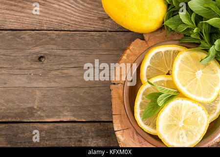 Bundle of mint and slices of lemon on old wooden background. Copy space. Top view. Rustic style Stock Photo