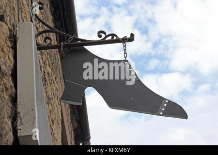 Sign in the form of an old fashioned ladies shoe, outside shoe shop. Stock Photo