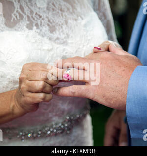 bride puts ring on finger of groom Stock Photo
