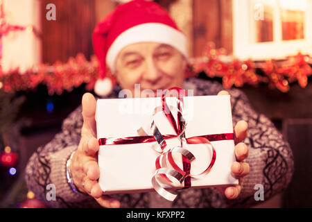 mature man holding a red christmas gift box in his hands Stock Photo