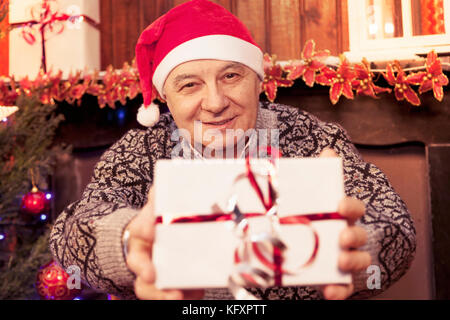 mature man holding a red christmas gift box in his hands Stock Photo