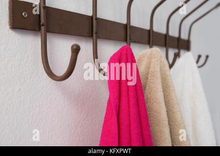 Close-up of colorful towels hanging on hook against white wall Stock Photo